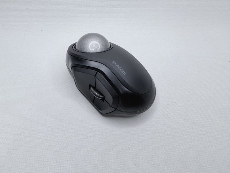 白い布の上に置かれた、手のひらに収まる大きさの黒いトラックボール。上面の左寄りに銀色の球があり、その手前にクリックボタンとホイールが並んでいる